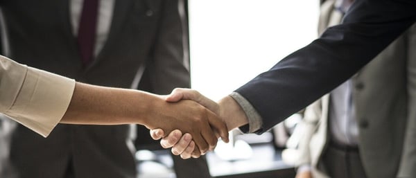 Management consultant salary: Two people in business attire shaking hands