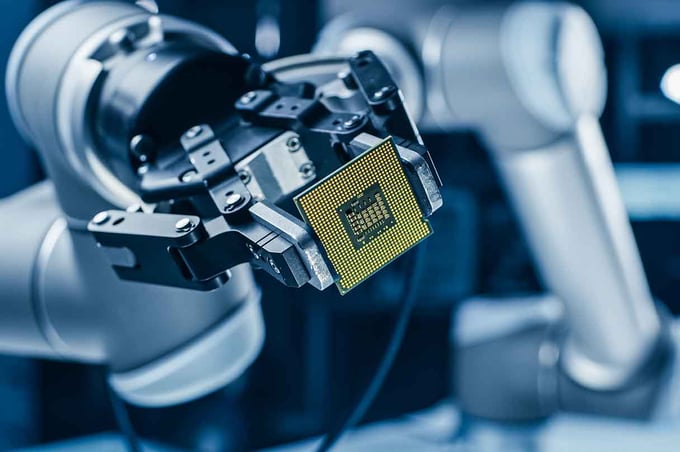 Robot arm placing a semiconductor chip in electronics manufacturing