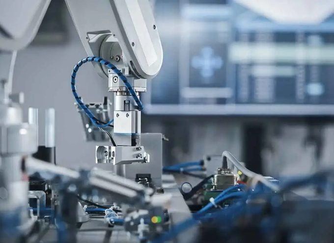 Roboterarm bestückt Bauteile in einer Montagezelle
